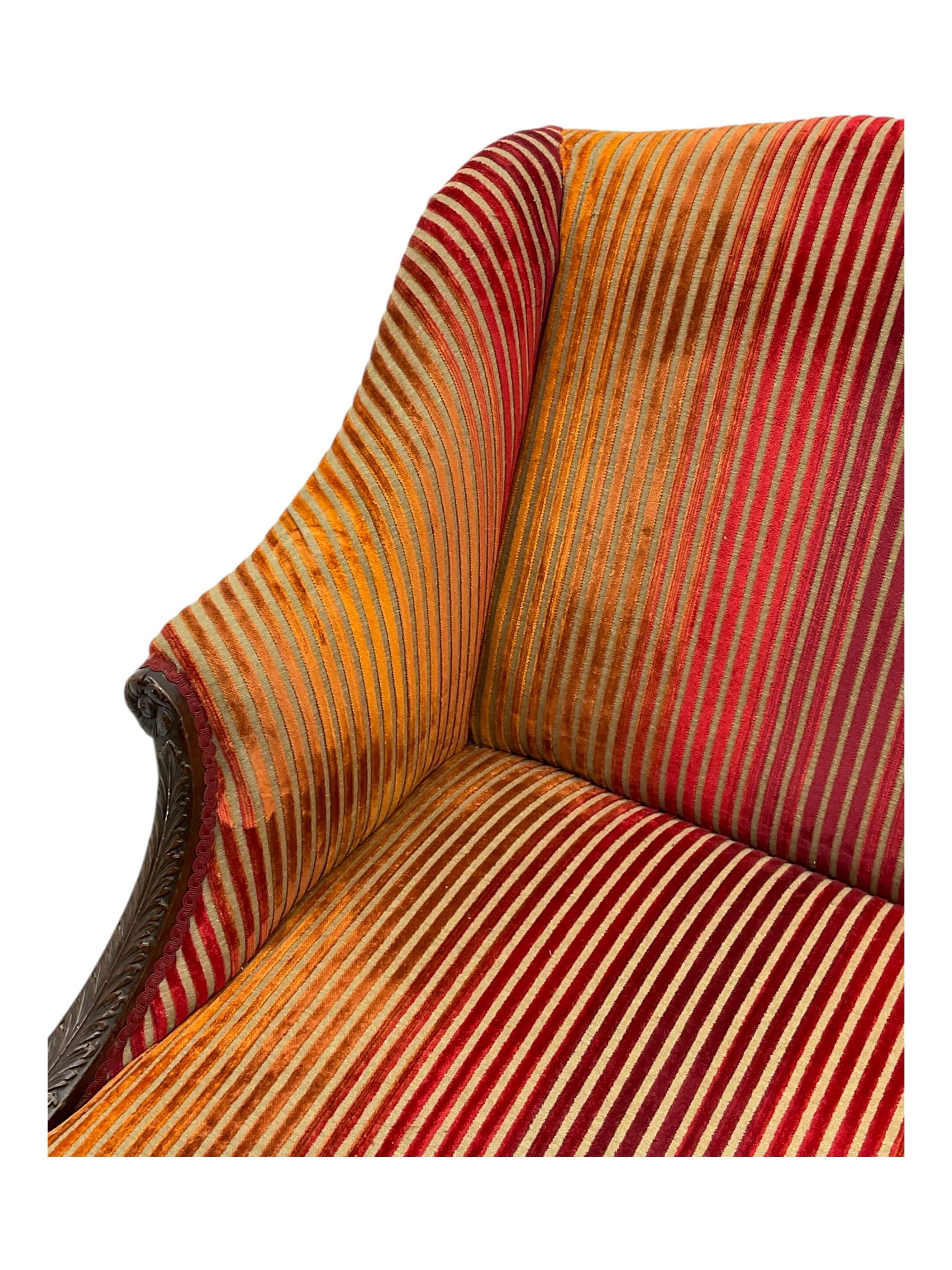 Mid-19th century mahogany two-seat sofa, upholstered in striped velvet fabric, the shaped backrest leading to outward-curved arms, carved apron with scrolling foliate details, raised on cabriole supports terminating in claw and ball feet