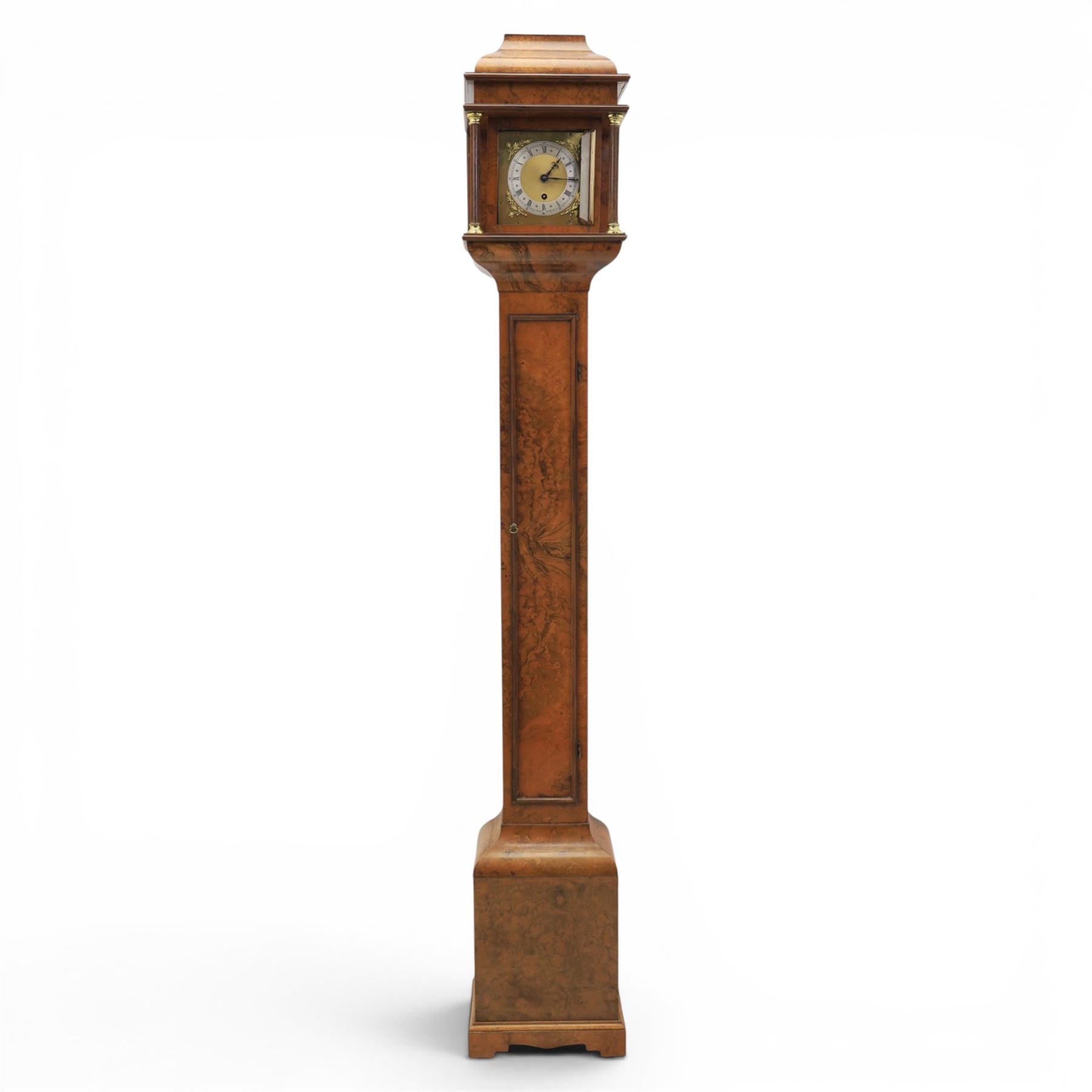 Early 20th century walnut small longcase clock, brass dial with silvered Roman numeral chapter ring and pierced black hands, the figured walnut case with shaped projecting hood, long moulded trunk door and stepped plinth base