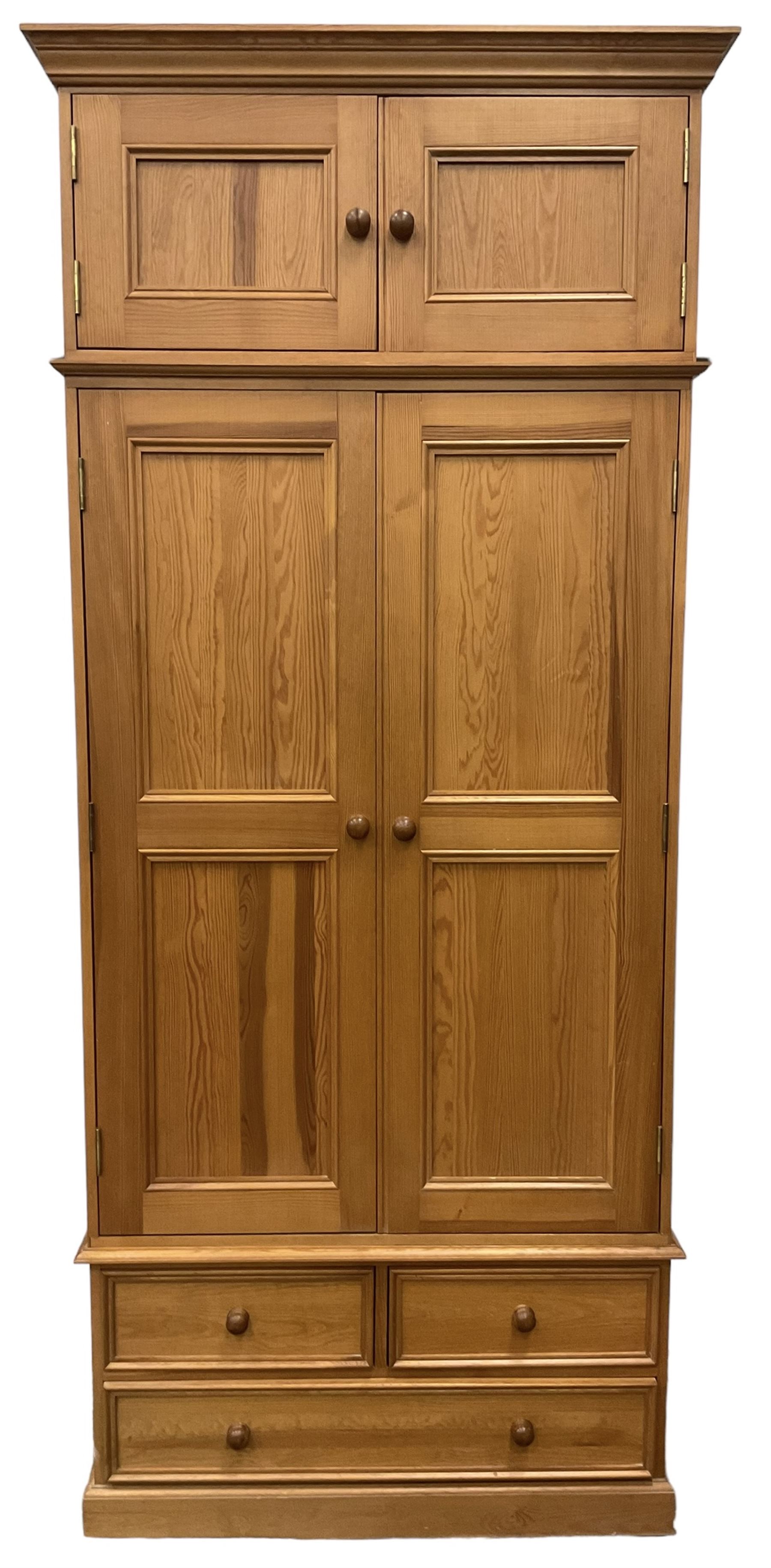 Solid pine double wardrobe, fitted with top box, enclosed by panelled doors, two short and one long drawer, on plinth base 
