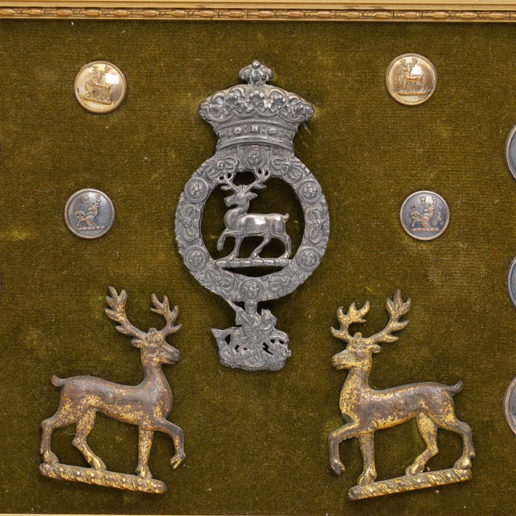 Collection of twenty two 19th century livery buttons with stag motif, badge with stag and St George design and two gilt stag  badges, framed 18cm x 44cm 