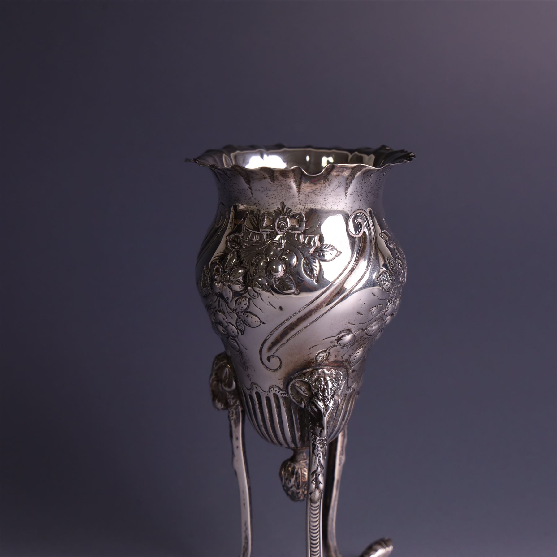 Late Victorian silver vase, of baluster form with fluted rim, the body with embossed floral decoration, upon three tall legs with ramshead mounts, hallmarked William Comyns & Sons, London 1890, H13.5cm