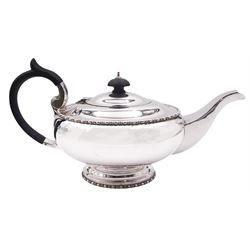 1920's silver teapot, of squat circular form upon a spreading circular foot, with bead and dart borders, and ebonised handle and finial, hallmarked Walker & Hall, Sheffield 1922, approximate weight 18.27 ozt (568.2 grams)