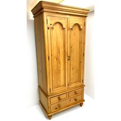 Classical pine double wardrobe, two doors enclosing hanging rail above two short and one long drawer, typically supports 