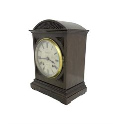 German - Early 20th century eight-day mantle clock, in an oak case with an elliptical top and carving to the front of the case, on a stepped plinth with padded feet, Silvered dial with Roman numerals, minute track and steel spade hands, retailed by Brownlee & Sons, Edinburgh, rack striking movement, striking the hours and half hours on a coiled gong. With pendulum. 