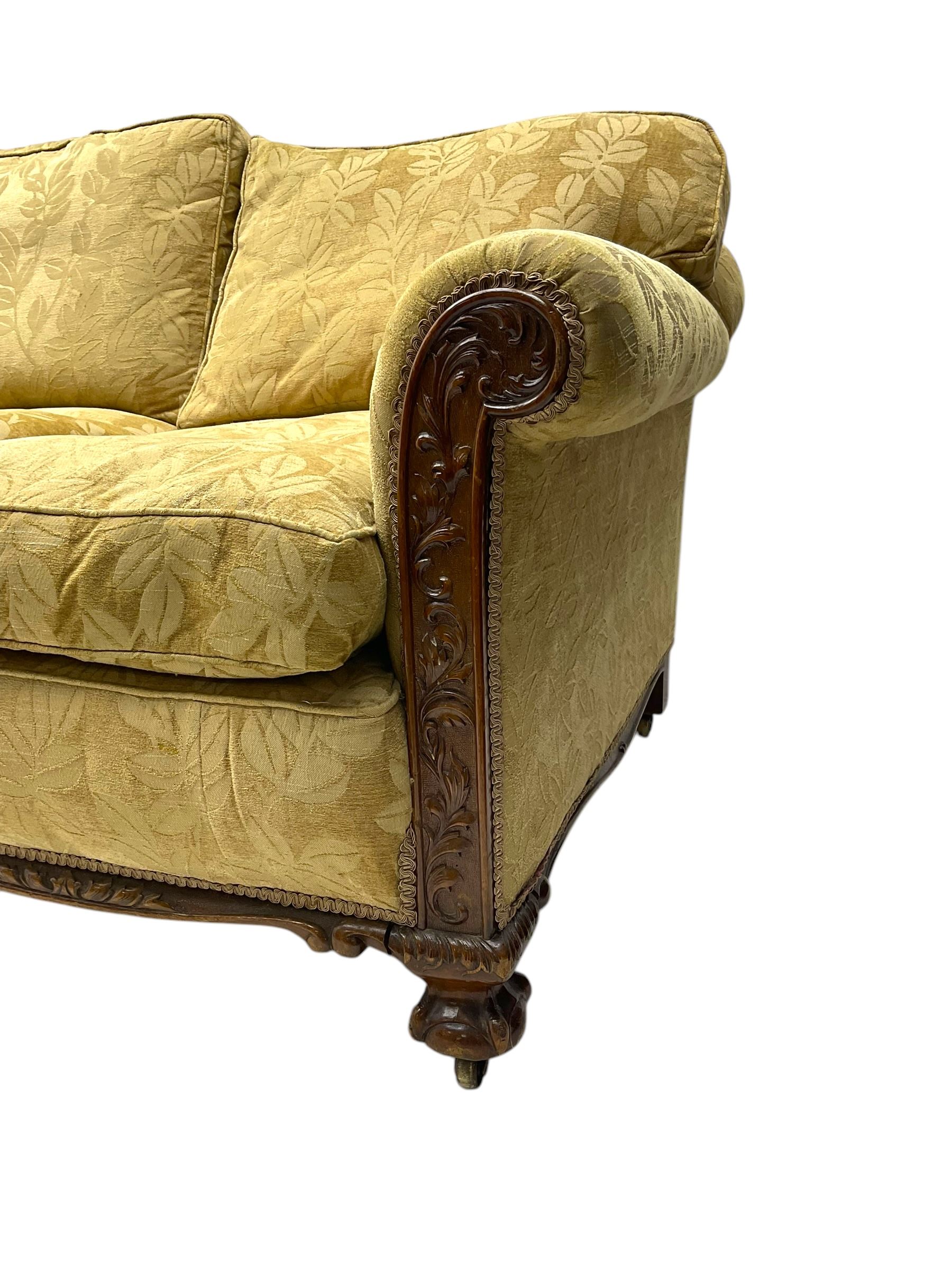 Early 20th century mahogany framed three-piece lounge suite - three-seat camelback sofa (W203cm, D105cm); pair of matching armchairs (W95cm, D96cm); upholstered in neutral foliate pattern fabric, carved with trailing leafy branches, ball and claw carved feet with brass castors 