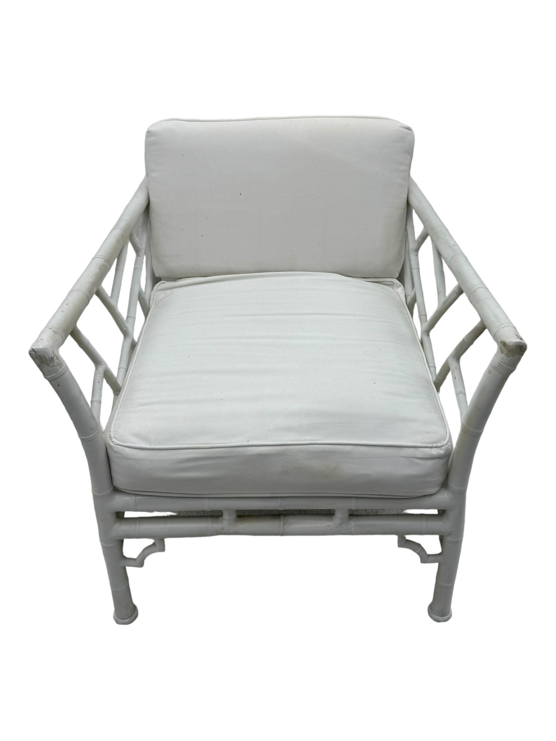 Late 20th century faux bamboo conservatory sofa, white painted frame with geometric openwork back and sides, loose cream cushions, on cylindrical supports (W134cm, D76cm, H80cm); matching armchair (W75cm, D76cm, H80cm); matching coffee table with glass insert (W46cm, D45cm, H36cm)