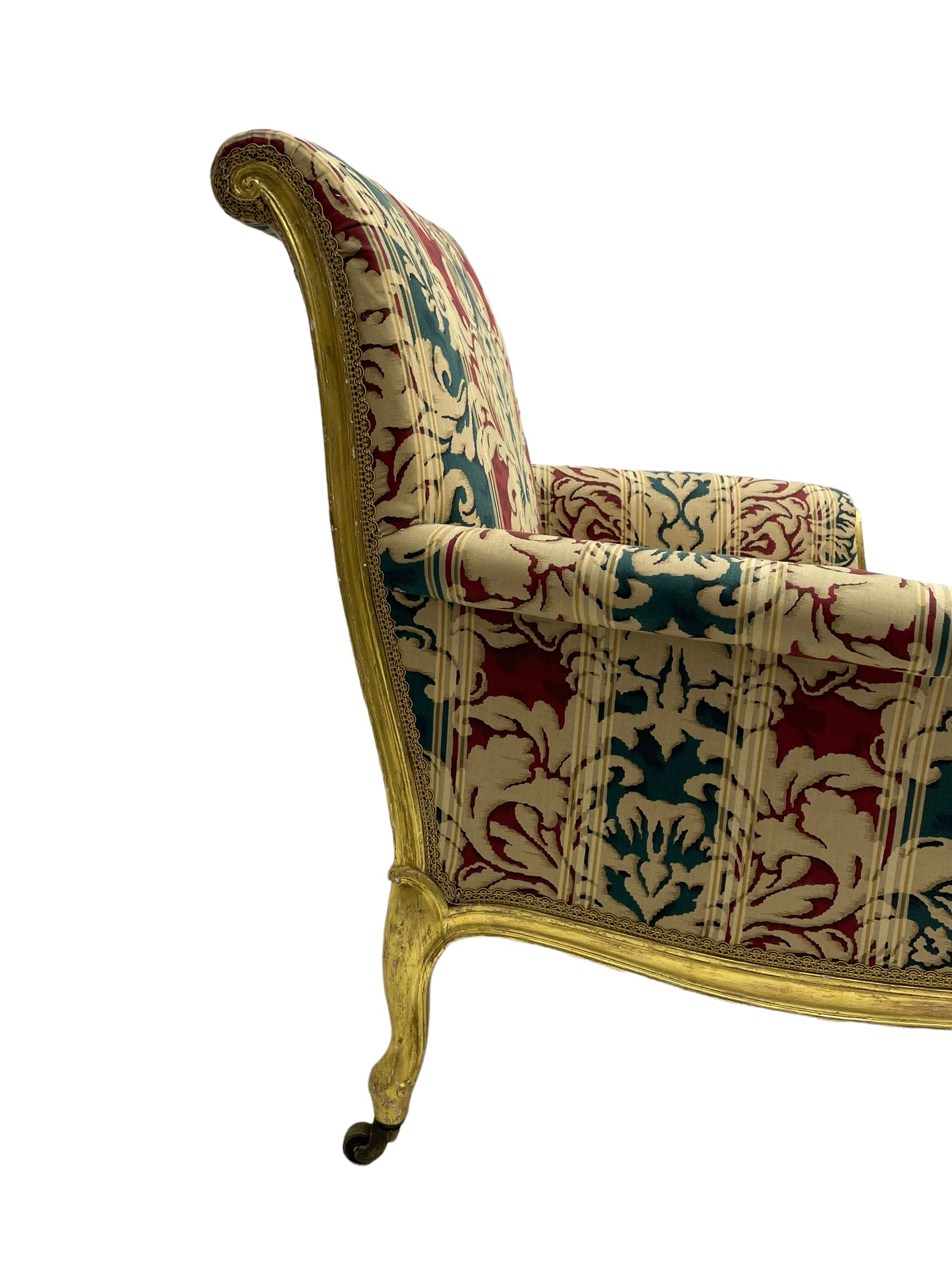 William Bertram & Son of London - pair late 19th century giltwood armchairs, moulded frame with scroll carved back and arm terminals, upholstered in striped fabric with foliate pattern, on shell carved cabriole supports, the brass castors stamped 