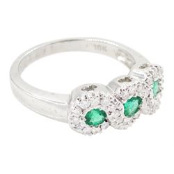 18ct white gold emerald and diamond triple cluster ring, three round cut emeralds, surrounded by round brilliant cut diamonds, the gallery with pierced trefoil motifs, stamped, total emerald weight approx 0.30 carat, total diamond weight approx 0.30 carat