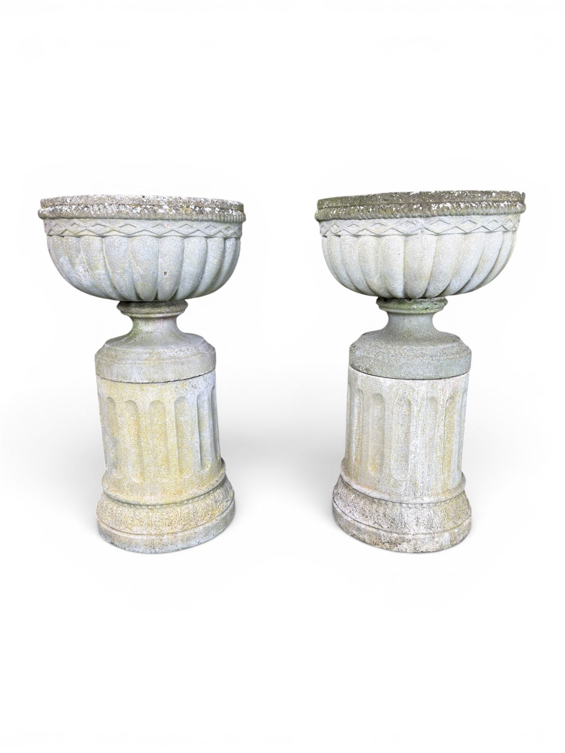 Four 20th century good quality weathered cast stone pedestal urns, circular lobed bowls with rope twist and lattice border, raised on squat base with fluted columns