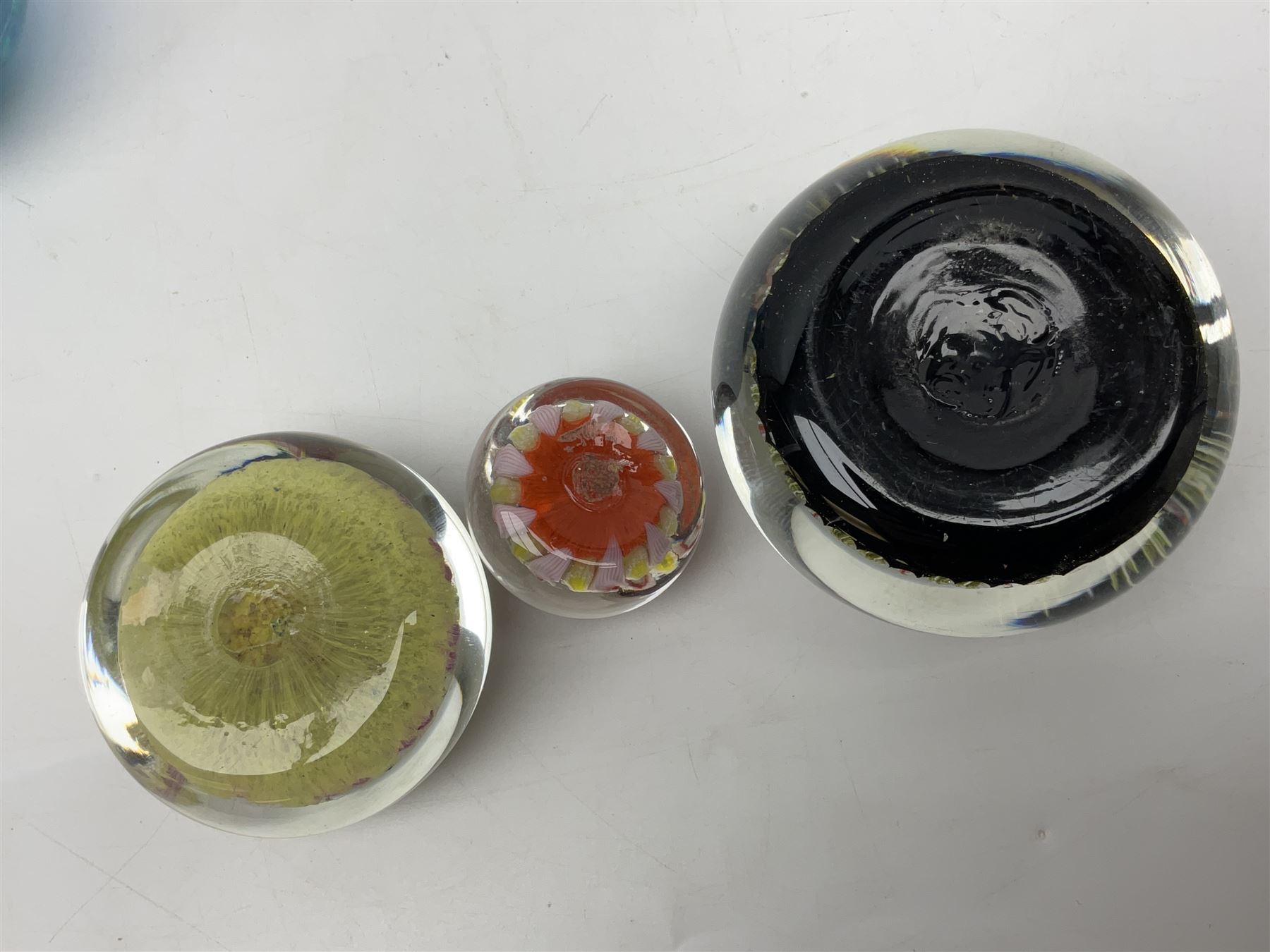 Three millefiori paperweights, together with a green glass dump paperweight with air bubble inclusions, Caithness Daisy and Cauldron paperweights and two small Caithness glass vases, tallest H9cm