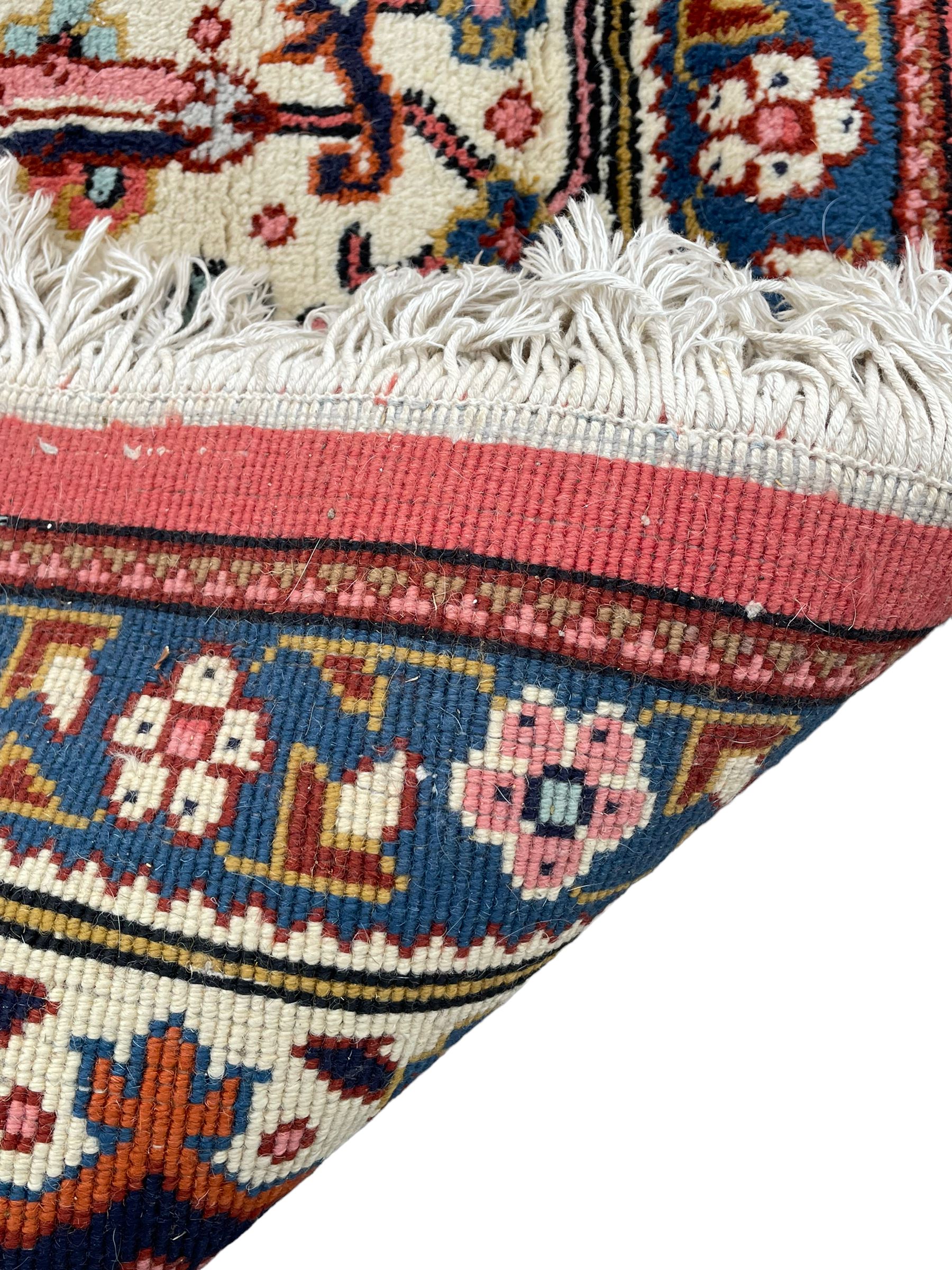 Large Persian carpet, the geometric and stylised floral medallion on rust ground field decorated with stylised plant motifs, guarded ivory border with repeating pattern