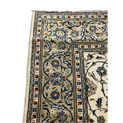 Persian Kashan ivory ground carpet, overall floral design, the field decorated with scrolling and interlaced leafy branches interspersed with palmettes, scrolling border decorated with stylised plant motifs, within floral pattern guard stripes 