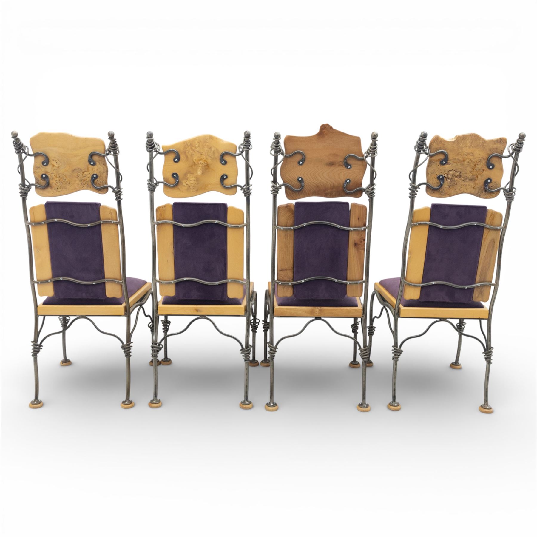 Paul Hodgkiss Designs of Glasgow - contemporary shaped elm dining table with wrought iron base; with set ten (8+2) matching high-back dining chairs, table of organic form above an elaborate wrought iron supports, with central elm stretcher, the chairs with en suite with matching wrought iron work burred elm headrest, purple velour upholstery with drop in seat     

Table: W 102cm, L 243cm, H 74cm
Chairs: W 56cm, D 52cm, H 130cm