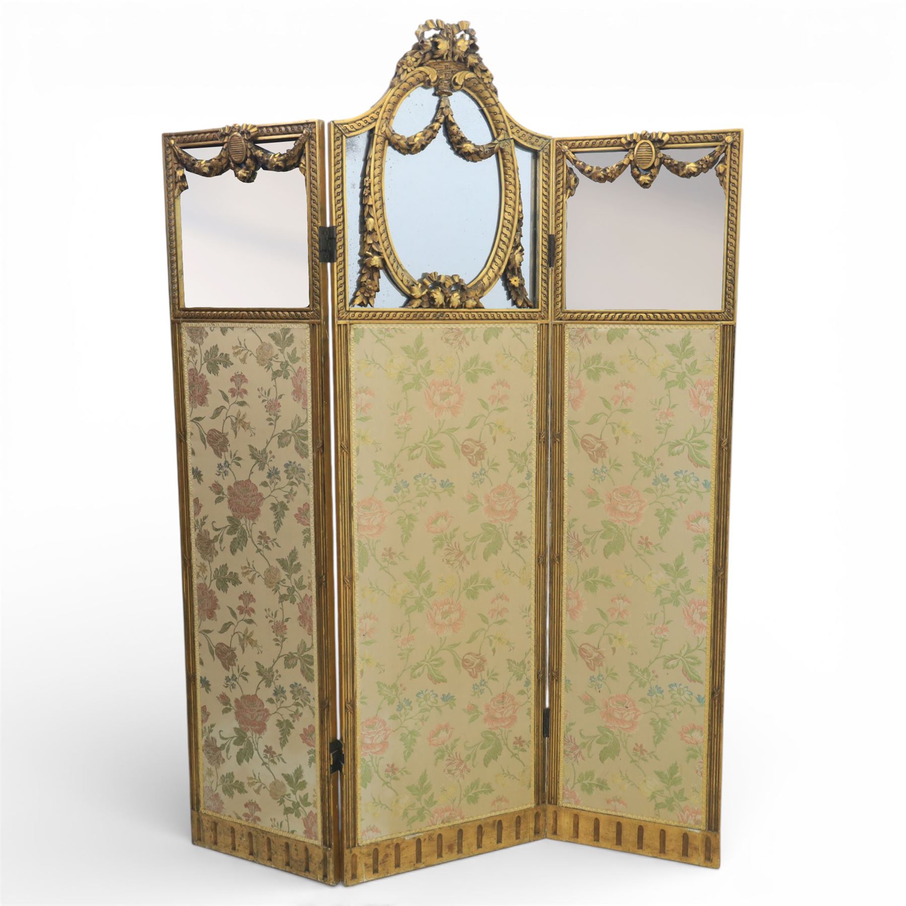 Late 19th century French Louis XIV style giltwood three fold dressing screen, each panel upholstered in floral fabric within fluted borders, with mirrored panels to tops set within moulded frames with foliate and ribbon swags 
