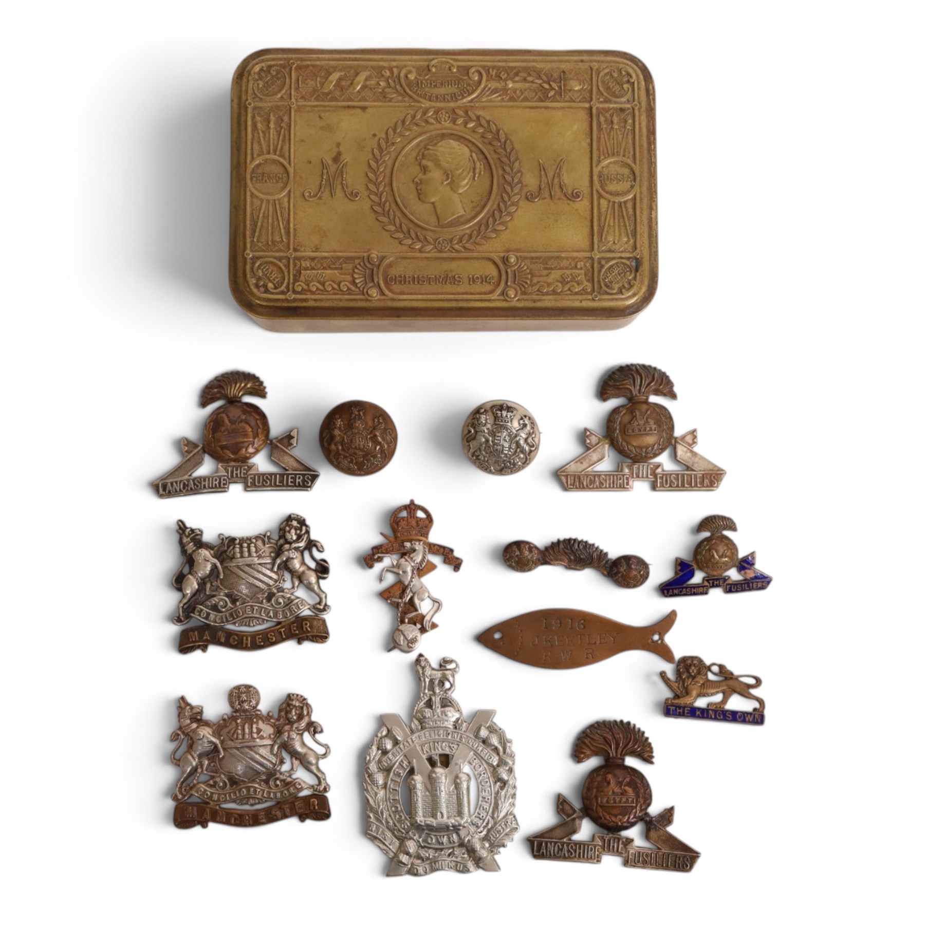  WWI Queen Mary 1914 Christmas tin, together with various cap badges including Lancaster Fusiliers, Manchester Regiment and King's Own Scottish Boarders  