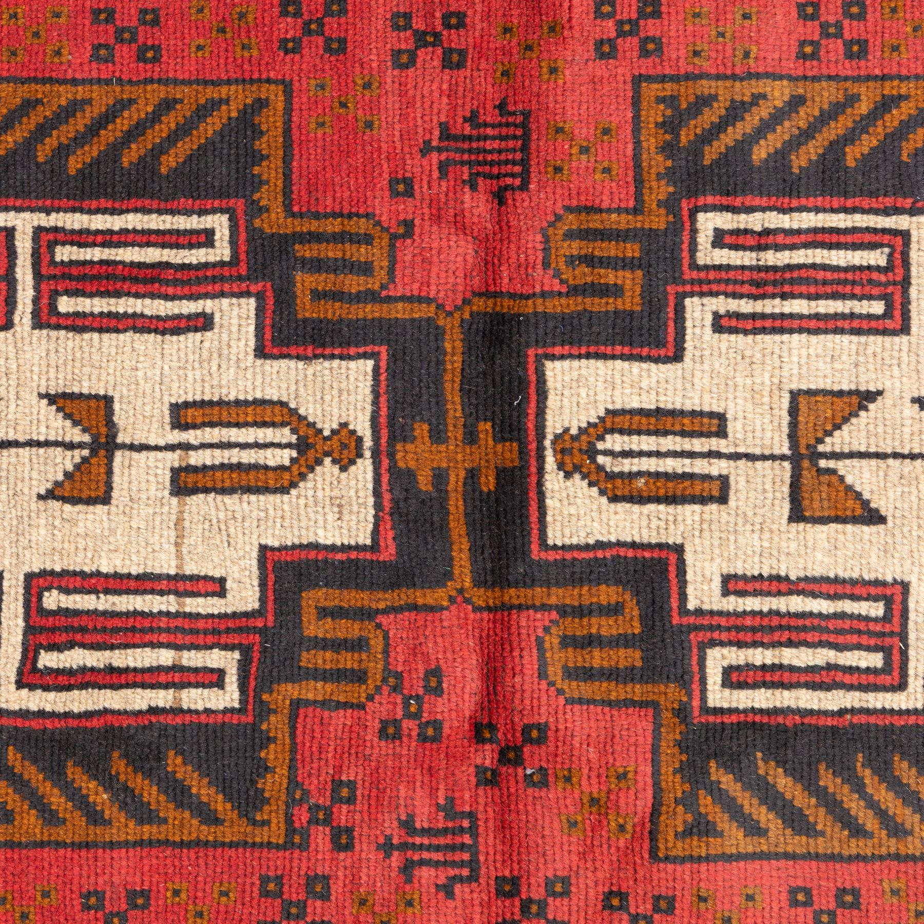Turkish Anatolian rug, crimson ground, with stepped geometric medallions in ivory, brown, and black within angular striped borders in tones of red and ochre 