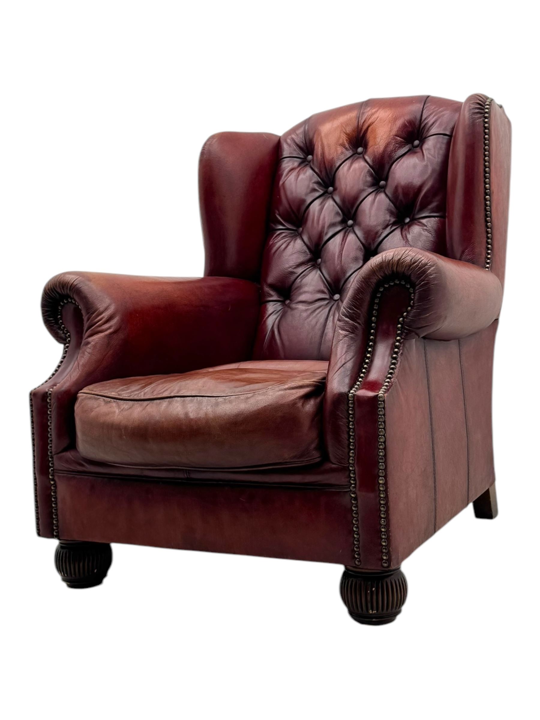 Tetrad - pair of 'Oskar' wingback armchairs, deep-buttoned oxblood leather upholstery with rolled arms and brass stud trim, raised on turned and reed moulded feet