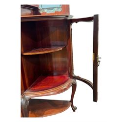 Late 19th century mahogany mirror back cabinet, shaped C-scroll pediment decorated with carved acanthus leaf cartouche and shells, shaped canopy top with applied foliate carvings over triple bevelled mirror back, central cupboard enclosed by panelled door carved with musical instruments, scrolls and shells, flanked by two glazed cabinets, on acanthus leaf carved cabriole supports united by undertier 