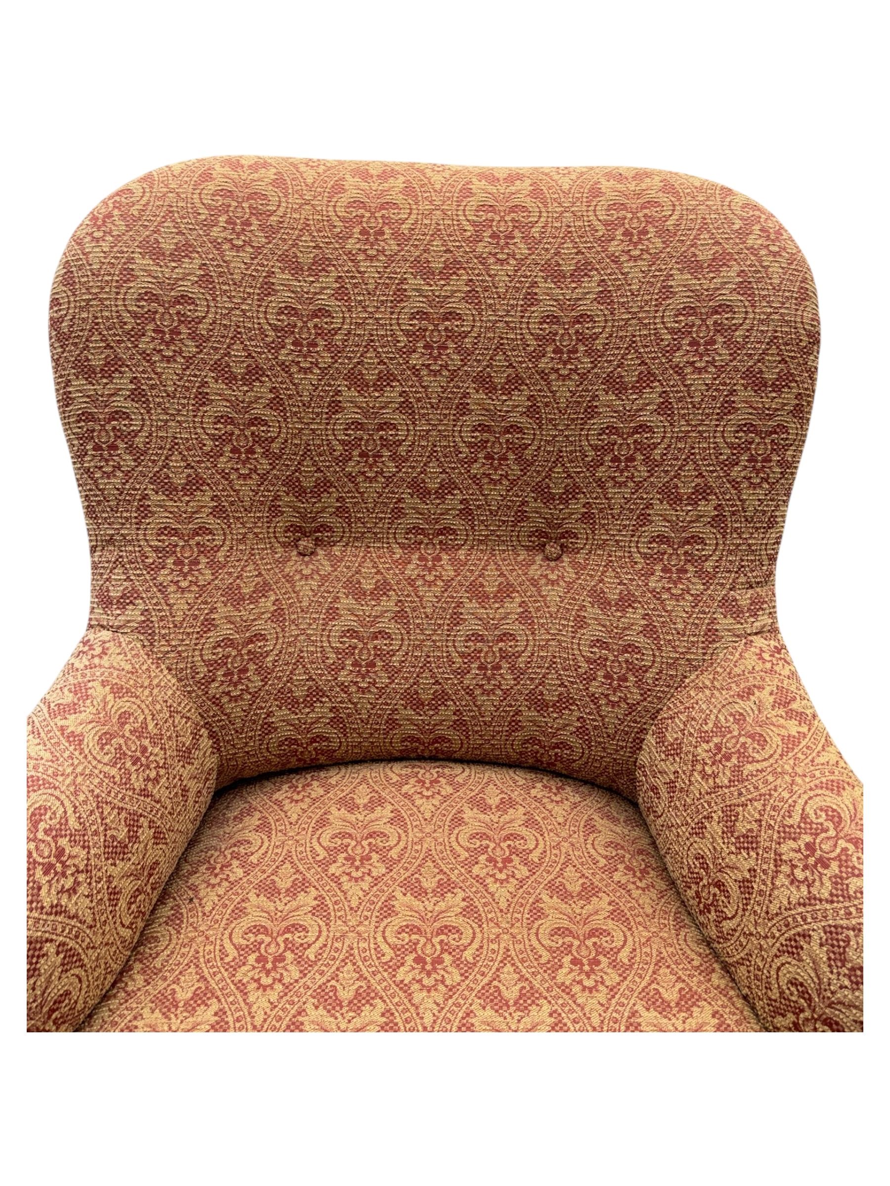 Late Victorian upholstered armchair, with high camel back and deep seat, padded arms and backrest in crimson and cream damask-style fabric, raised on turned ebonised front supports with ceramic castors (H88cm, W65cm, D 60m); and an Edwardian bedroom chair with button upholstered rail back (H72cm, D64cm, W53cm) (2)