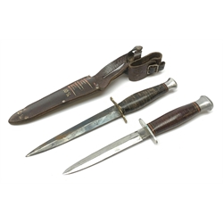American WW2 type fighting knife with 14cm steel double edged blade, brass crosspiece, leather bound grip and aluminium pommel, in leather sheath marked twice 10C/A L27cm overall; and another similar fighting knife without sheath (2)