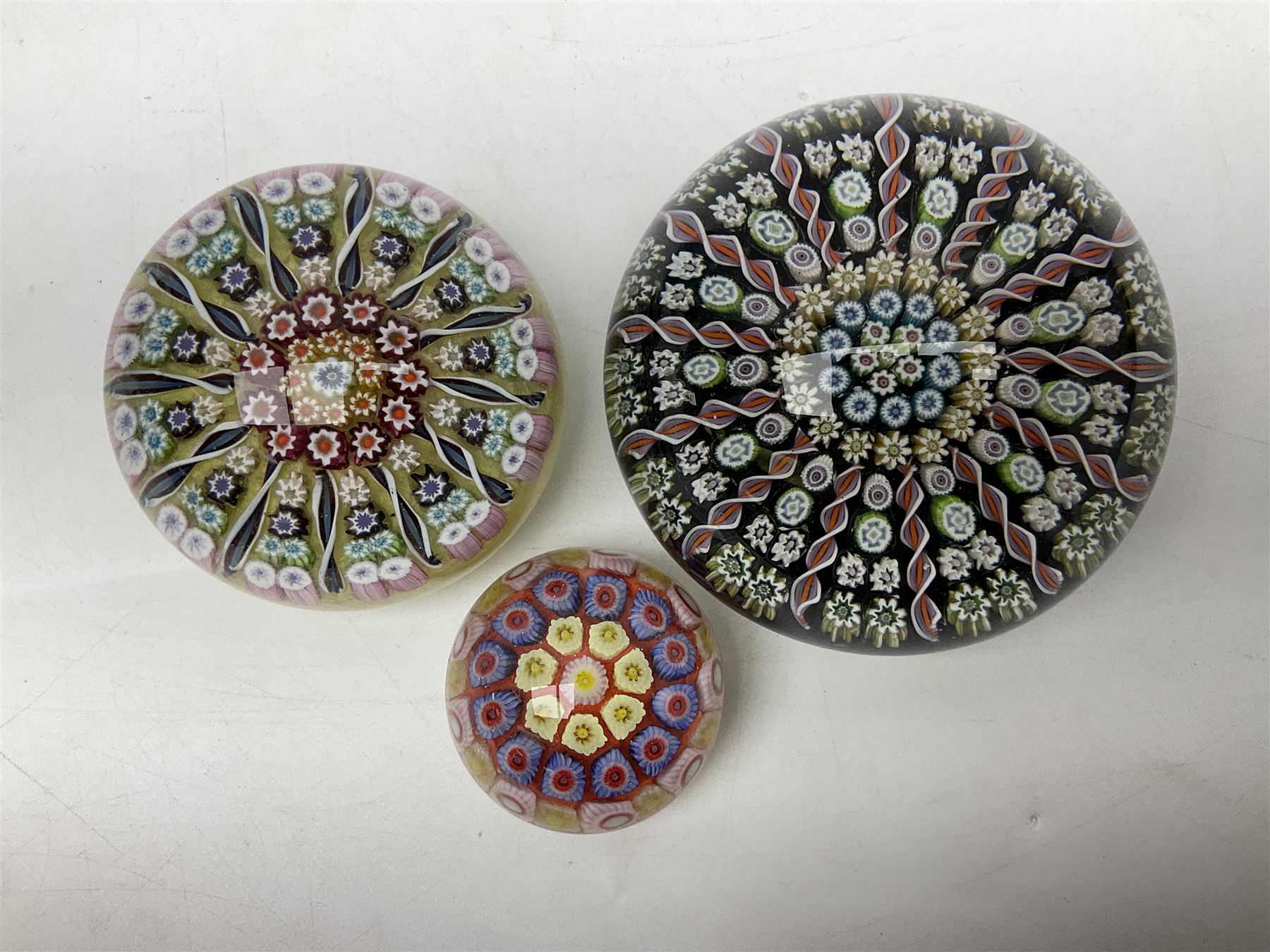 Three millefiori paperweights, together with a green glass dump paperweight with air bubble inclusions, Caithness Daisy and Cauldron paperweights and two small Caithness glass vases, tallest H9cm