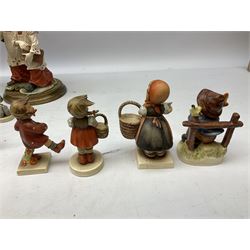 West German style figure modeled as a seated fox, together with seven Hummel figures, to include girl with guitar, boy seated on a fence, girl with basket etc 