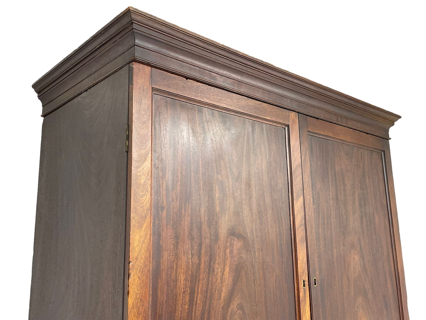 George III mahogany Gentleman's linen press, the projecting cornice over two panelled cupboard doors enclosing three sliding trays, the base fitted with two short over three long graduating cock-beaded drawers, lower moulded edge over bracket feet