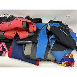 Collection of children's wet suits, including Odyssey Core long wet suit size 4/5 years, three Banana Bite short wet suits sizes 5 to 13 years and five other short wet suits.  