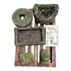 Collection of cast stone garden objects including mill stone, trough, planter, and faces