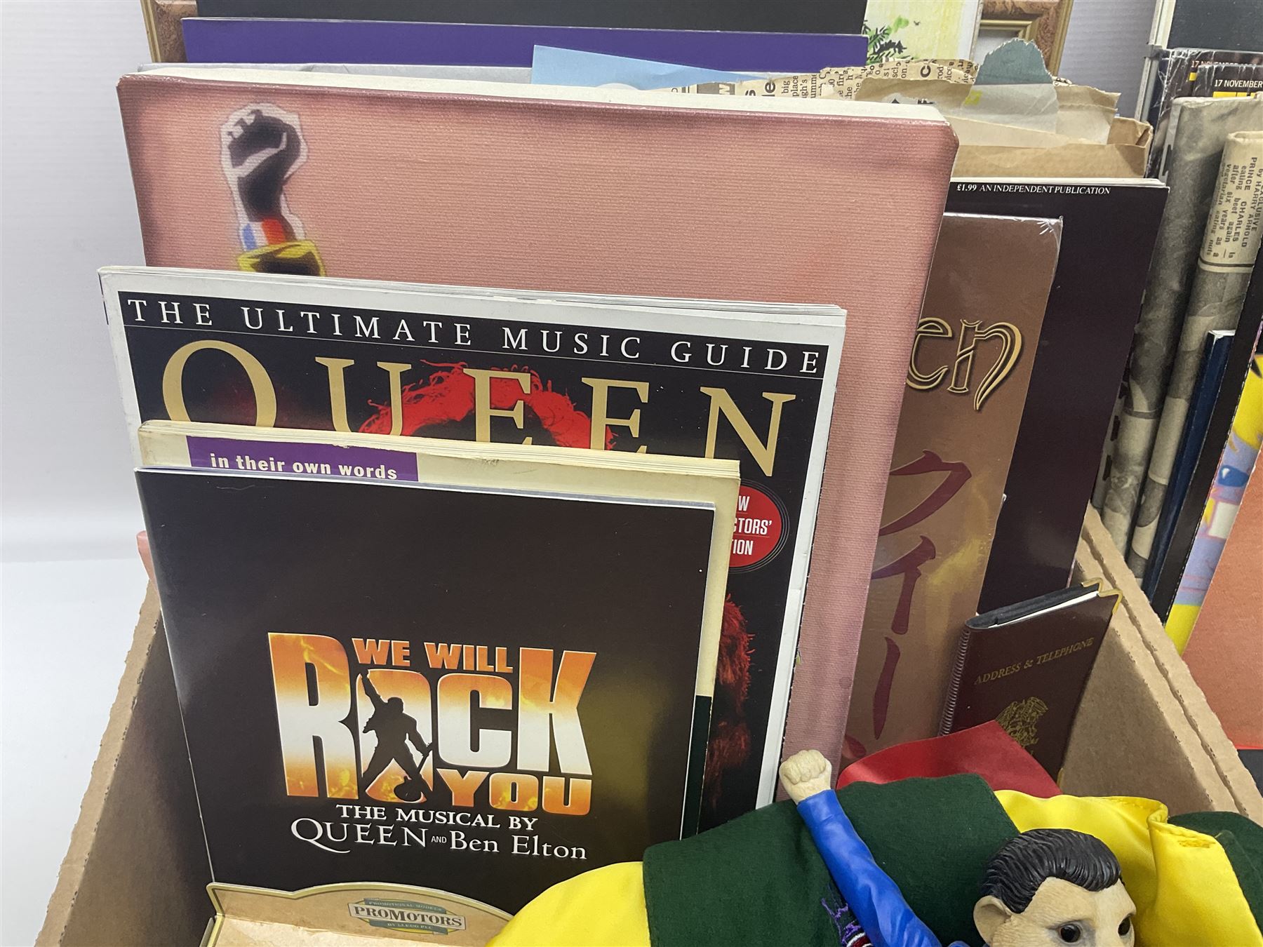 Mostly Queen and Freddie Mercury interest items, including pin badges, newspaper cuttings, diecast 'promotional' vehicles, special edition Pop Rocks figure of Freddie Mercury, VHS tapes, two charity certificates signed by Brian May and Roger Taylor, poster etc, in two boxes 