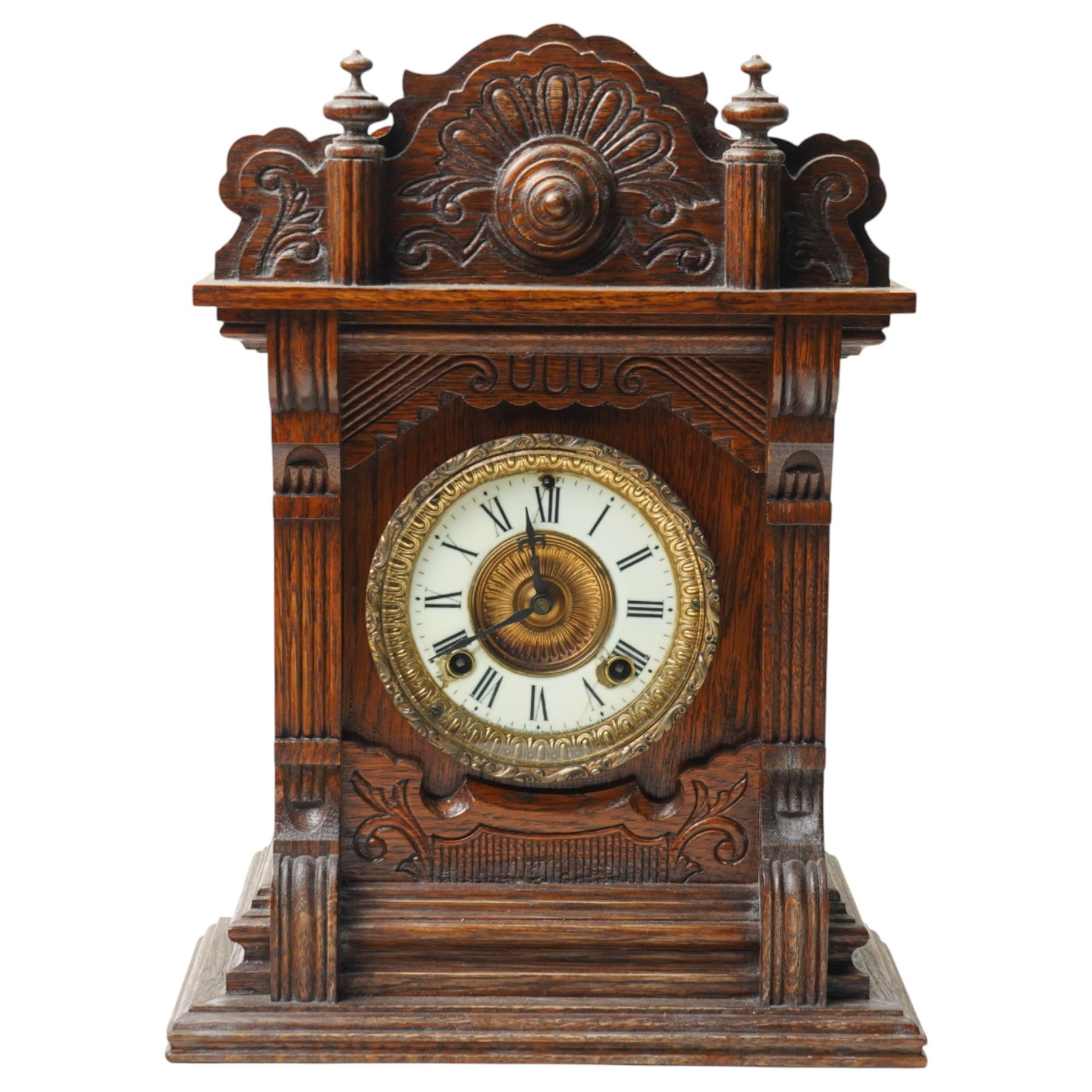 Late 19th century-8-day American Ansonia mantle clock, in a carved oak case with an enamel dial and gilt dial bezel, twin train spring driven movement striking the hours on a coiled gong. With pendulum.