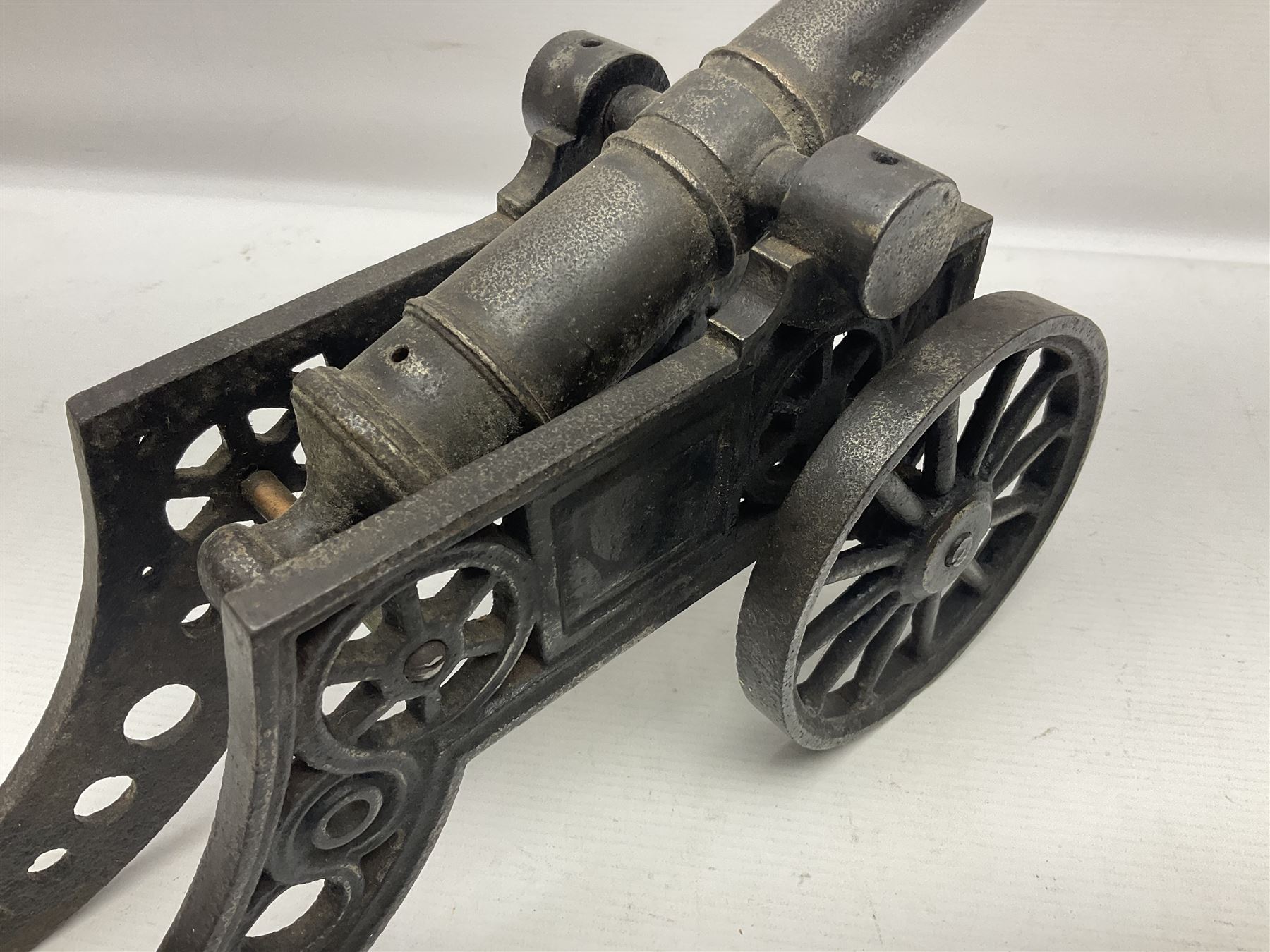 Victorian cast-iron and steel signal cannon, approximately half-inch bore, with 23cm ringed barrel and cylindrical trunnions, on a cast iron carriage with two twelve-spoked wheels and guilloche pierced swept back support, L43cm overall