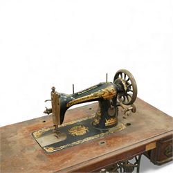 Early 20th century Singer treadle sewing machine, the black enamel machine with gilt floral and scroll transferwork set within a timber cabinet top with folding leaf, raised on cast-iron base with pierced geometric treadle and 'Singer' name stretcher, flanked by two small drawers
