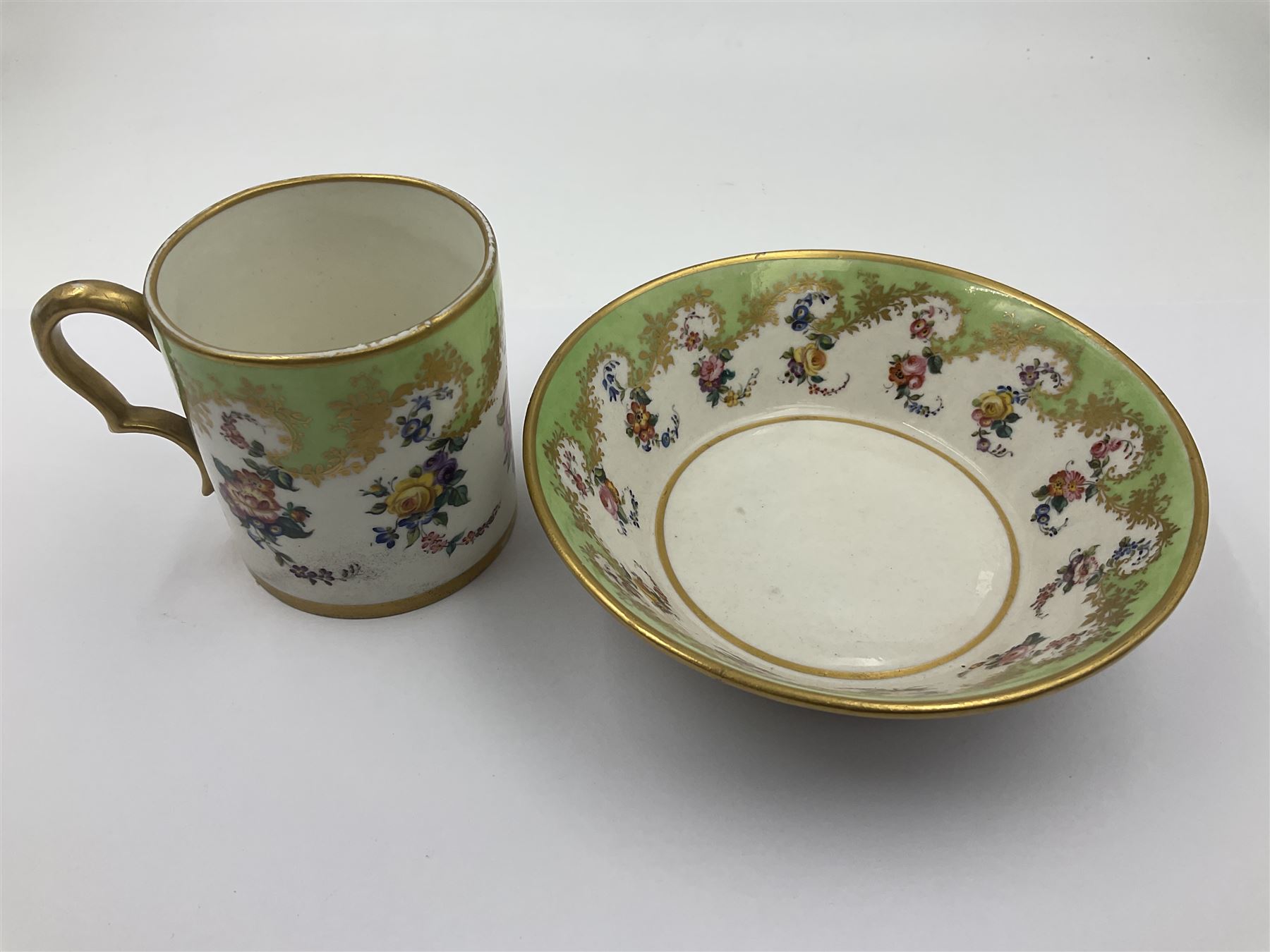 Sèvres soft paste porcelain coffee can and saucer with date code for 1754, painted and gilded with flowers, dangling from the shaped green border, interlaced LL monogram enclosing the date letter A above painters mark for Dodin, coffee can H7cm, saucer D14.5cm