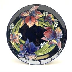 A Moorcroft footed dish decorated in the iris pattern upon a dark blue glazed ground, with impressed and painted marks beneath, D31.5cm