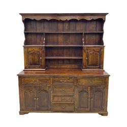 Traditional oak dresser, the moulded cornice over shaped apron, three heights plate rack fitted with two cupboards, the base fitted with six drawers and two double cupboards, panelled pointed ogee arched doors, on bracket feet