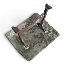 19th century cast iron boot scraper, mounted on a rectangular hewn stone slab base, with scrolled twin upright supports and scraper bar, in weathered finish