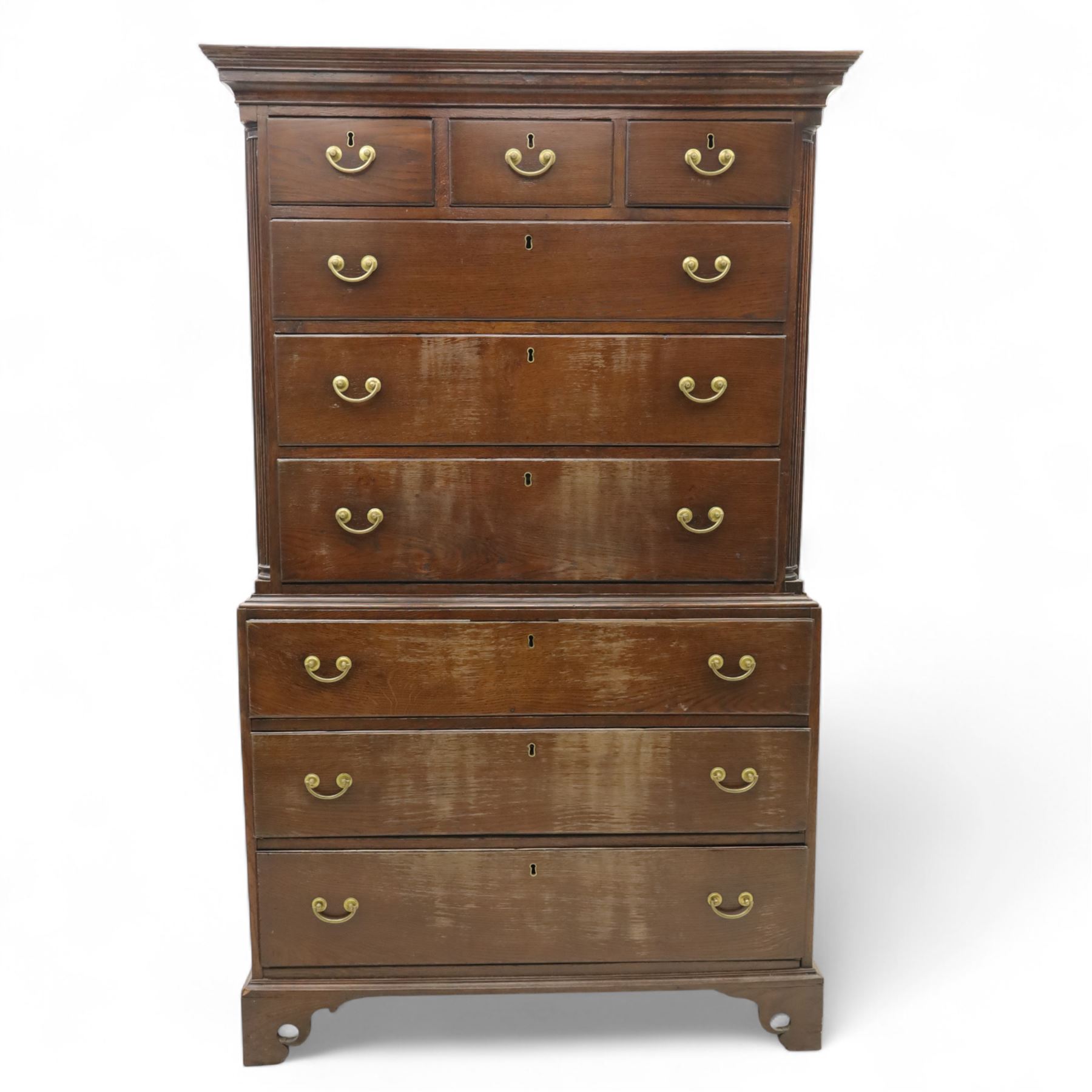 Mid 18th century oak tallboy chest, the projecting cavetto-moulded cornice over two short and three long drawers to the upper section, the lower section with three further graduated long drawers, each drawer with oak linings and fitted with later brass swan-neck handles, flanked by stop-fluted quarter columns, all raised on shaped bracket feet