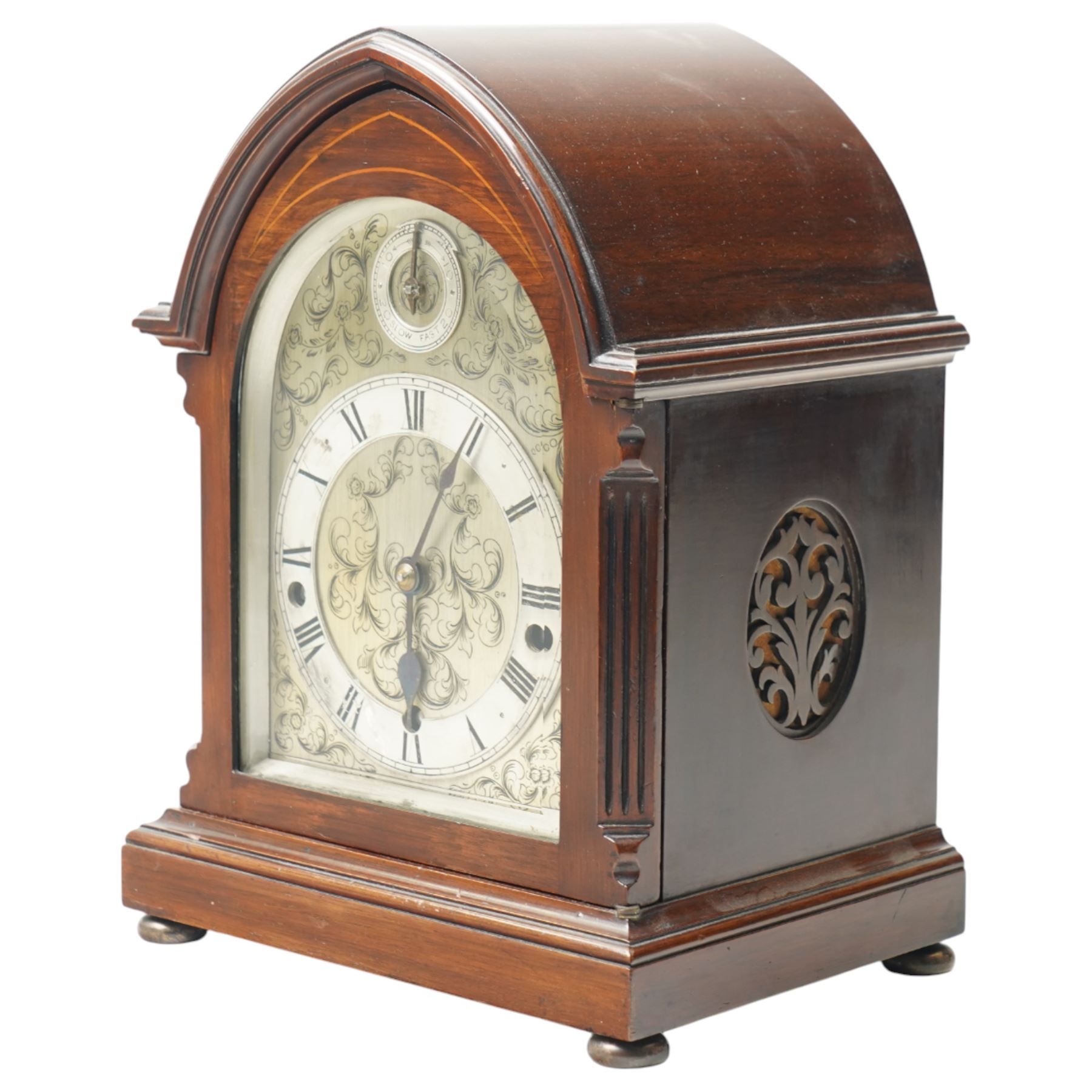 English-8-day 20th-century three train Westminster Chime Lancet clock in a mahogany case, with canted reeded quarter columns to the door and silk backed sound frets to the sides, fully silvered dial with decorative engraving and pendulum adjustment dial, silvered chapter with Roman numerals, minute track and spade hands, chiming the quarters and hours on five coiled gongs, With key, no pendulum. 

