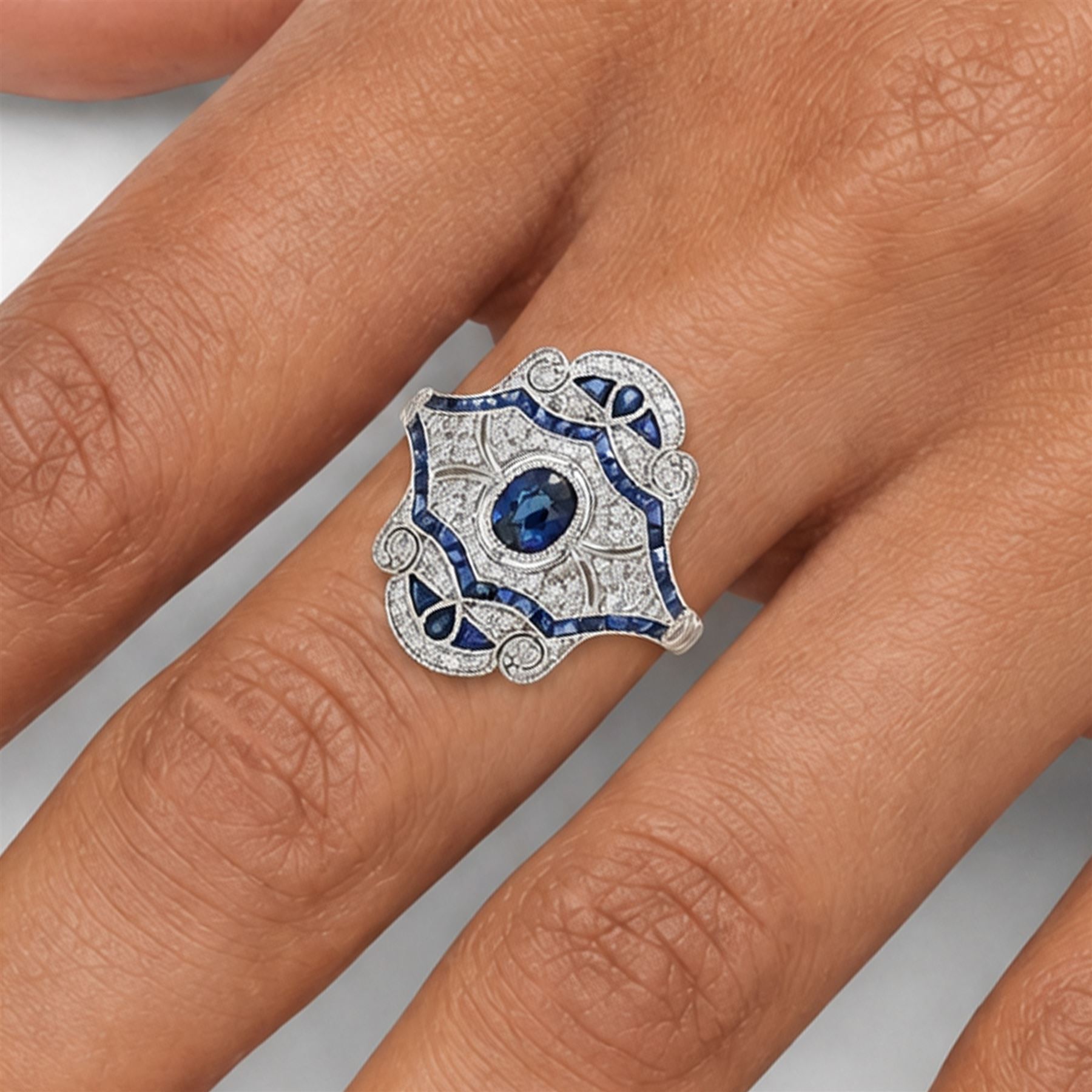 Platinum sapphire and diamond dress ring, milgrain set with a single oval cut sapphire, surrounded by single cut diamonds, calibre and vari-cut sapphires, in an pierced design setting, stamped PT 950, total sapphire weight 0.87 carat, total diamond weight 0.45 carat