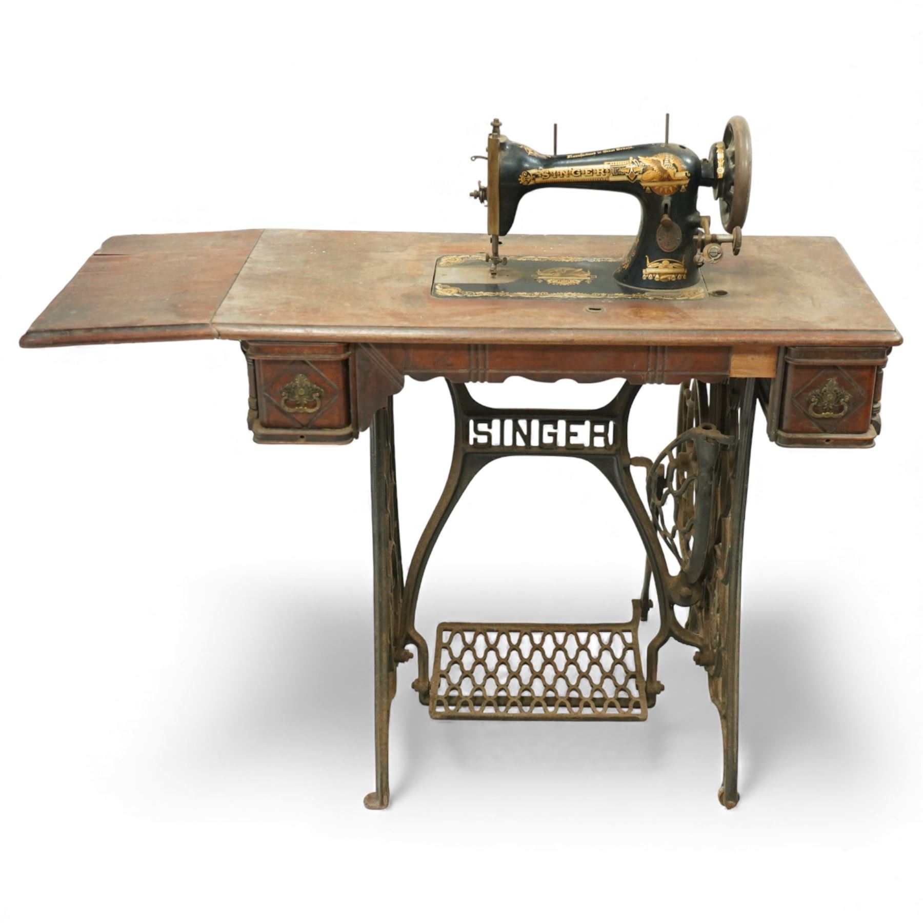 Early 20th century Singer treadle sewing machine, the black enamel machine with gilt floral and scroll transferwork set within a timber cabinet top with folding leaf, raised on cast-iron base with pierced geometric treadle and 'Singer' name stretcher, flanked by two small drawers