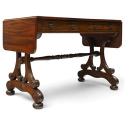 Fine 19th century figured mahogany sofa table, the rectangular twin drop-leaf top with rounded corners above two cock-beaded frieze drawers with opposing faux drawers, fitted with turned handles, raised on twin reeded and C-scroll-carved end supports with palmette-carved platform bases and compressed bun feet, united by a turned and foliate-carved stretcher