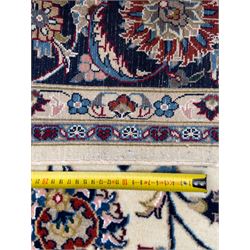 Northeastern Persian Meshed hand-knotted rug, ivory ground with an overall design of scrolling vines, palmettes, and rosettes in an indigo palette, soft blues, and madder, framed by a deep indigo border of lotus palmettes and flowerheads between multiple guard borders, 300cm x 202cm