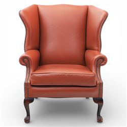 Georgian design red leather wingback armchair, with shaped back and scrolled arms, and close brass studded trim, upon cabriole front legs with claw and ball feet
