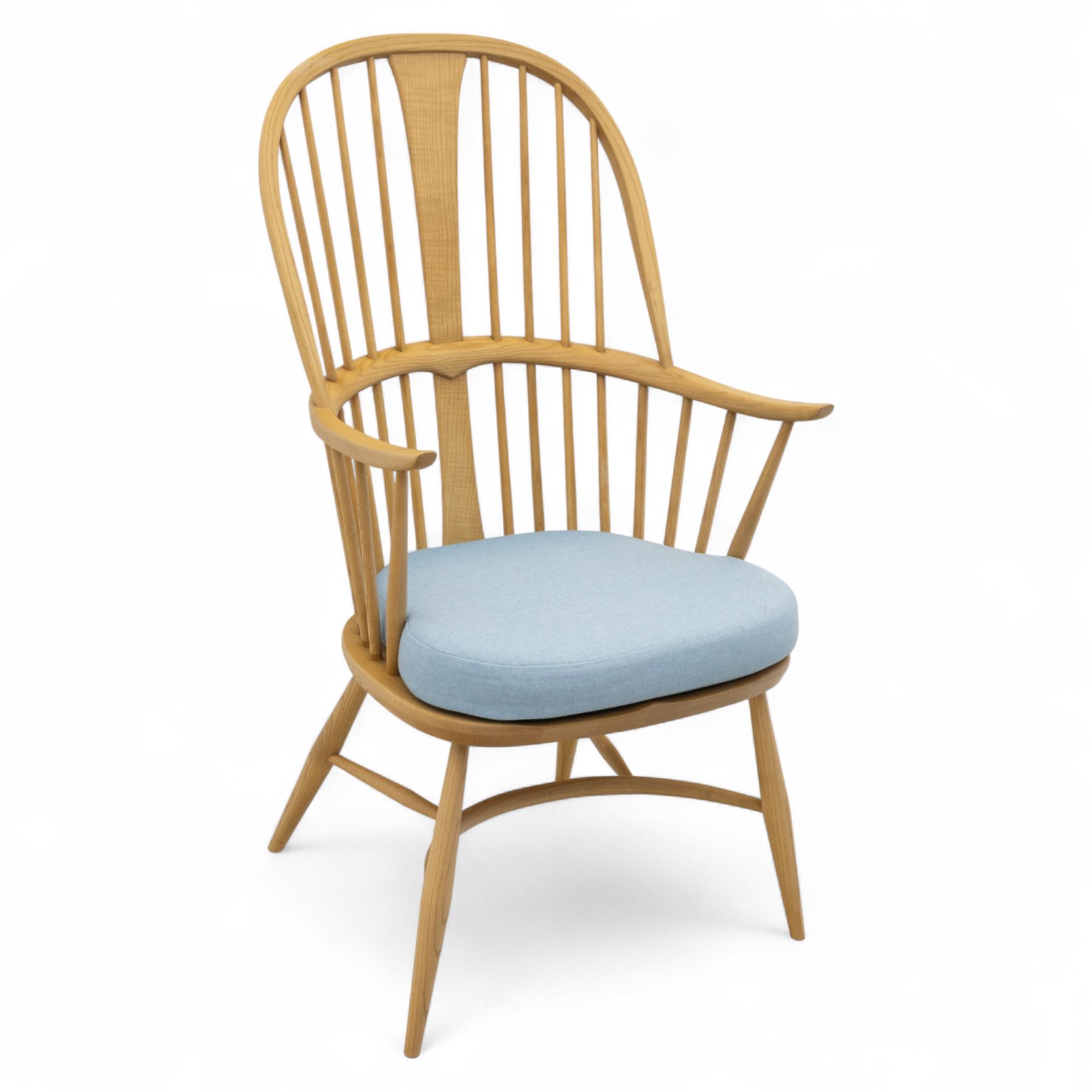 Ercol - ‘Chairmakers’ armchair, of traditional Windsor form in light ash, featuring a hoop back with four spindles and central splat, curved arms and turned supports, dished seat with upholstered blue cushion