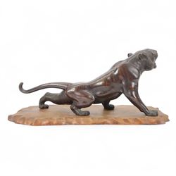 Japanese Meiji period bronze, modelled as a crouching tiger, its head raised in a roar, with glossy stripes and naturalistic mane, with seal mark for Mitsumoto saku, upon a carved softwood stand, bronze H20.5cm L46cm
