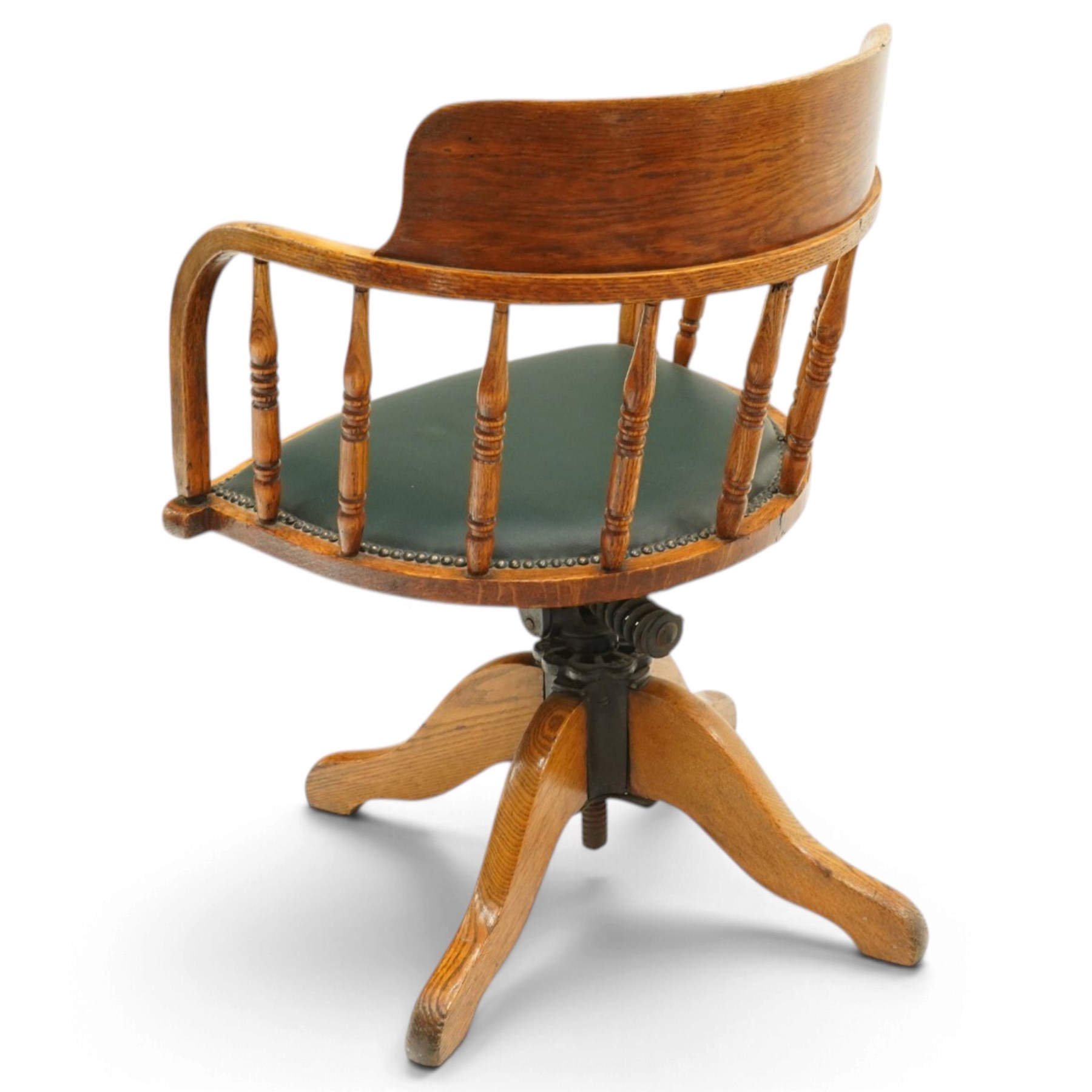 Edwardian oak captains swivel desk chair of tub form, shaped cresting rail over spindle supports and green-leather upholstered seat, foliate apron over swivel action and four-spoke base
