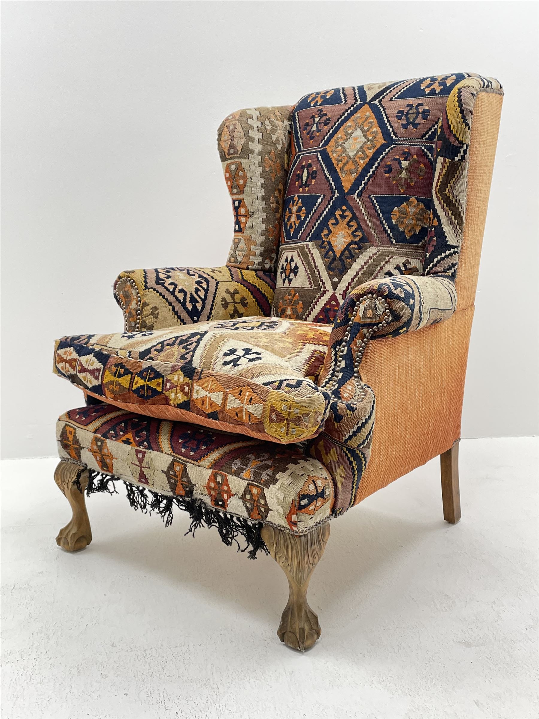 Late 20th century beech framed wingback armchair, sprung seat and back upholstered in kilim cover, acanthus carved cabriole supports with ball and claw feet