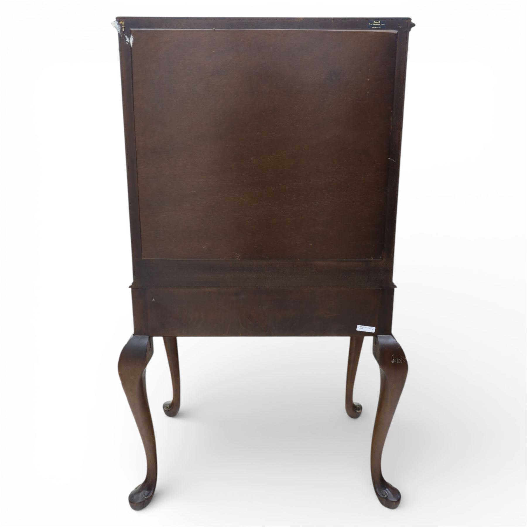 20th century Queen Anne style mahogany cocktail cabinet, moulded cornice above a pair of fielded panel doors with decorative strap hinges and central escutcheon, opening to a mirrored interior fitted with tiered shelves with brass gallery rails, pull-out glass inset mixing slide above three short drawers, shaped apron on cabriole supports with carved shell knees terminating in pad feet