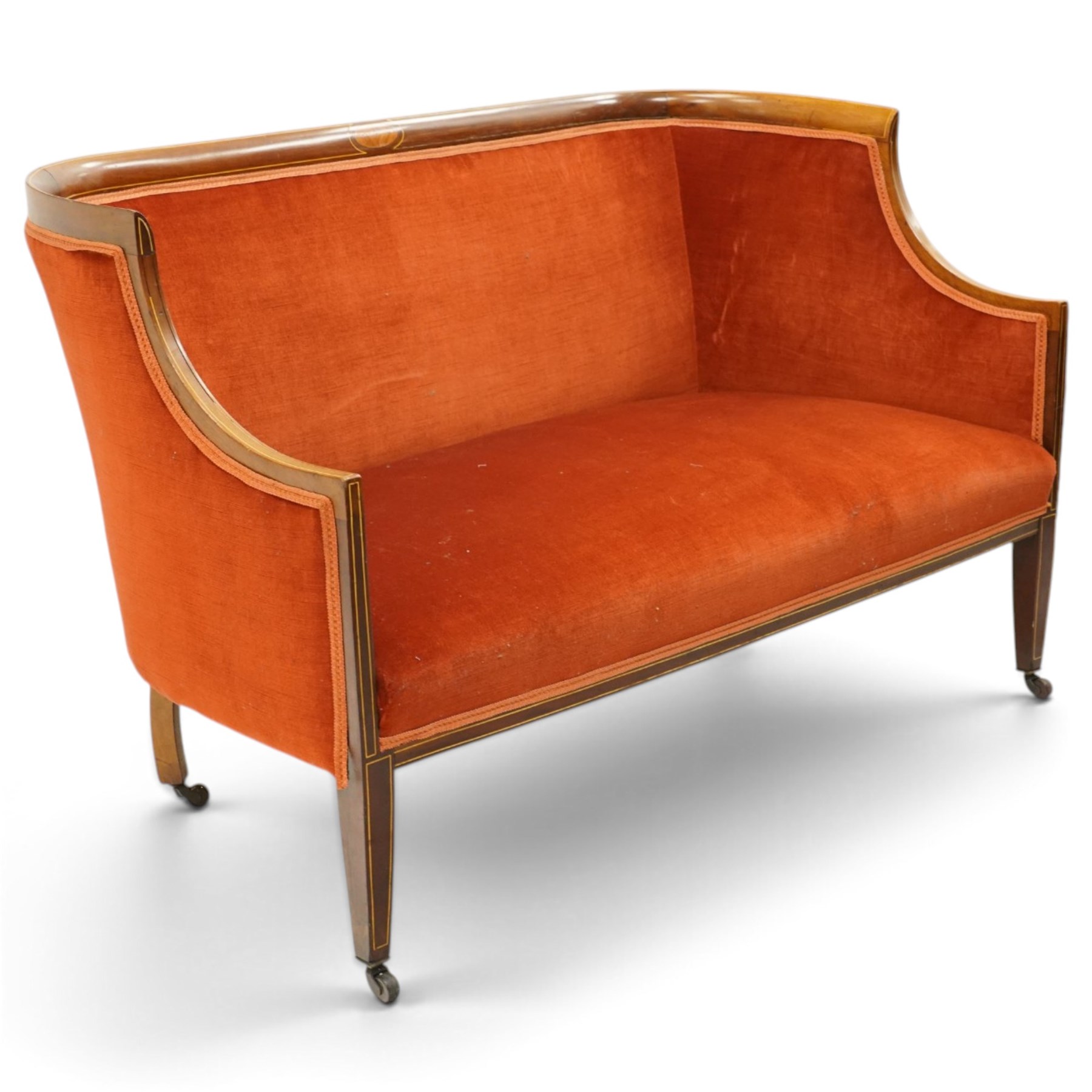 Edwardian inlaid mahogany tub two seater settee, traditional shape with satinwood stringing, upholstered in crimson fabric with sprung seat, on square tapering supports with castors